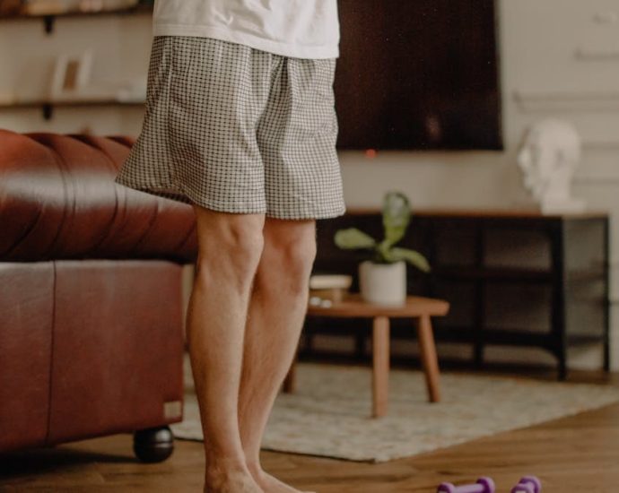 Man practicing balance exercise at home with a focus on legs and barefoot posture.