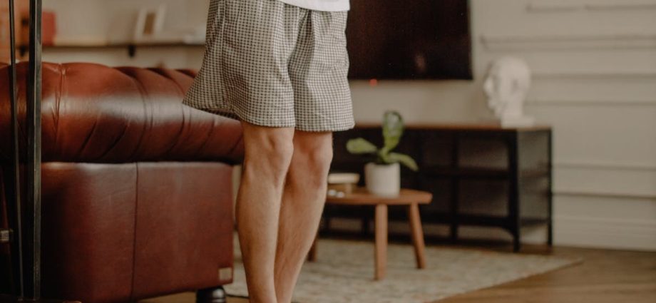 Man practicing balance exercise at home with a focus on legs and barefoot posture.